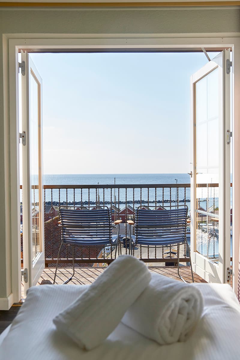 Room with sea view through the terrace doors and balcony chairs